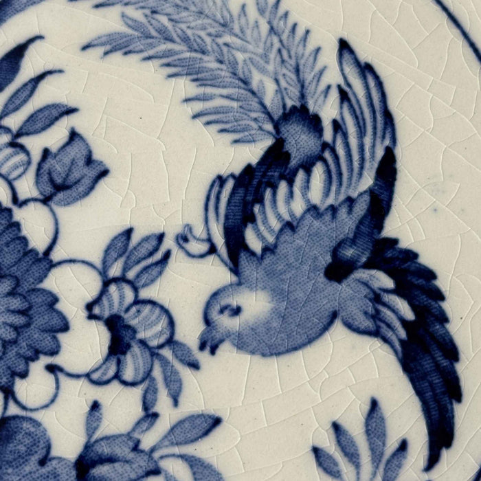 Close-up of blue flying bird and floral transfer decoration with visible crazing in the white glaze.
