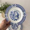 Hand holding one vintage Wood & Sons Yuan blue and white plate with bird, floral, and geometric decoration.