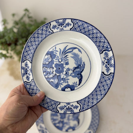 Hand holding one vintage Wood & Sons Yuan blue and white plate with bird, floral, and geometric decoration.