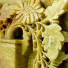 Close-up detail of pierced floral carving on a vintage soapstone bookend showing layered leaves and openwork detail