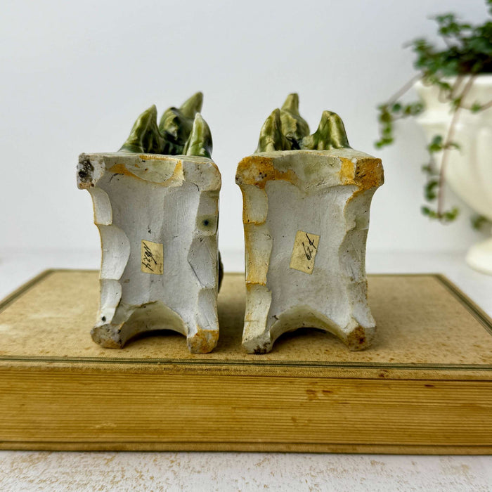 Underside view of both vintage foo dog figures showing unglazed bases and old inventory labels