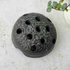 Vintage Japanese ceramic flower frog with an organic domed form and dark earthy glaze on a light surface