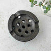 Undersie of vintage Japanese ceramic flower frog with an organic domed form and dark earthy glaze on a light surface
