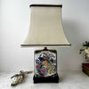 Vintage chinoiserie-style peacock accent lamp with original cream shade, featuring colorful peacocks, peonies, and navy and gold detailing on a dark wood base