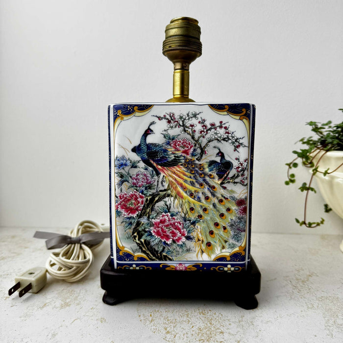 Close-up of the dark wood base and lower ceramic body of a vintage peacock accent lamp