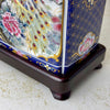 Close-up of the dark wood base and lower ceramic body of a vintage peacock accent lamp