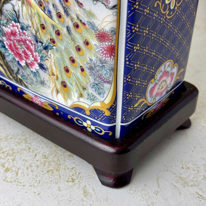 Close-up of the dark wood base and lower ceramic body of a vintage peacock accent lamp
