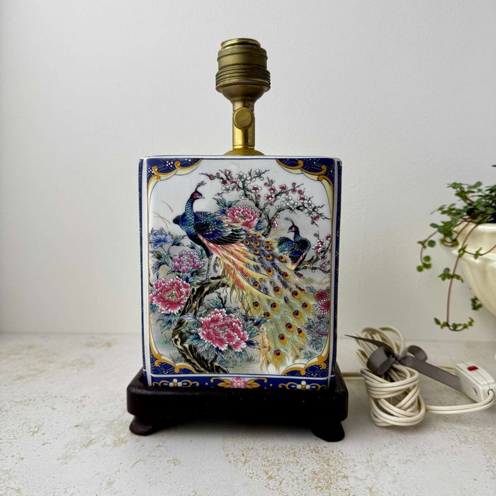 Back view of the vintage peacock lamp without the shade, showing the ceramic body, socket, and dark wood base
