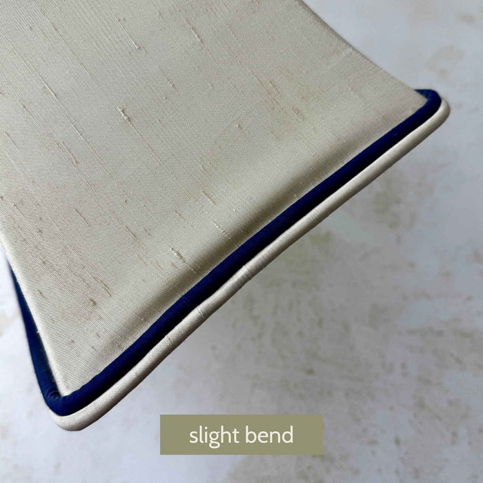 Close-up of the original cream lamp shade showing a slight bend to one side panel and navy trim detail
