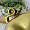 Close-up of the curled tail and leaf-like detail on one vintage brass pig bookend.