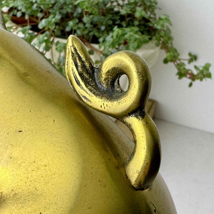 Close-up of the curled tail on the second vintage brass pig bookend, showing darkened recessed details.
