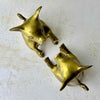 Overhead view of the pair of brass pig bookends showing their pointed ears, snouts, raised hooves, and rounded bodies.