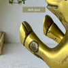 Close-up of a dark spot on the front leg of one vintage brass pig bookend.