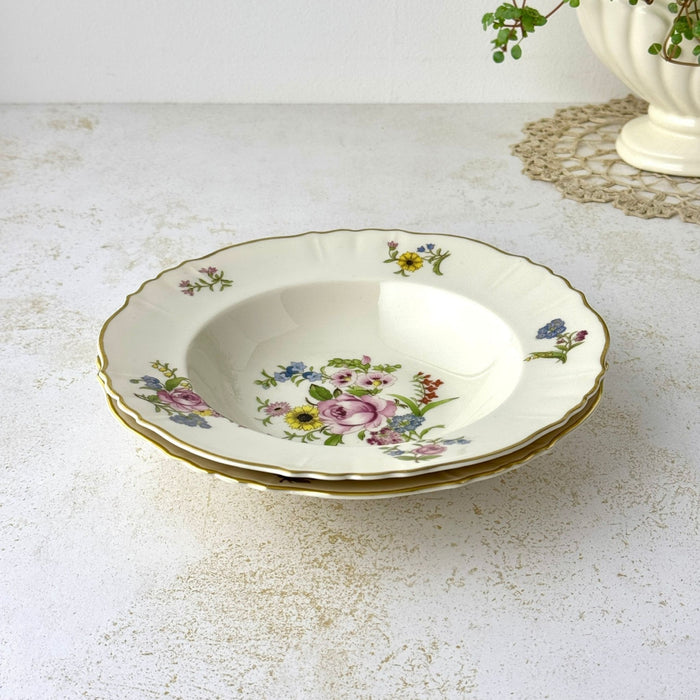 Angled view of two stacked vintage Syracuse China Portland bowls with colorful floral decoration and gold-trimmed scalloped rims.