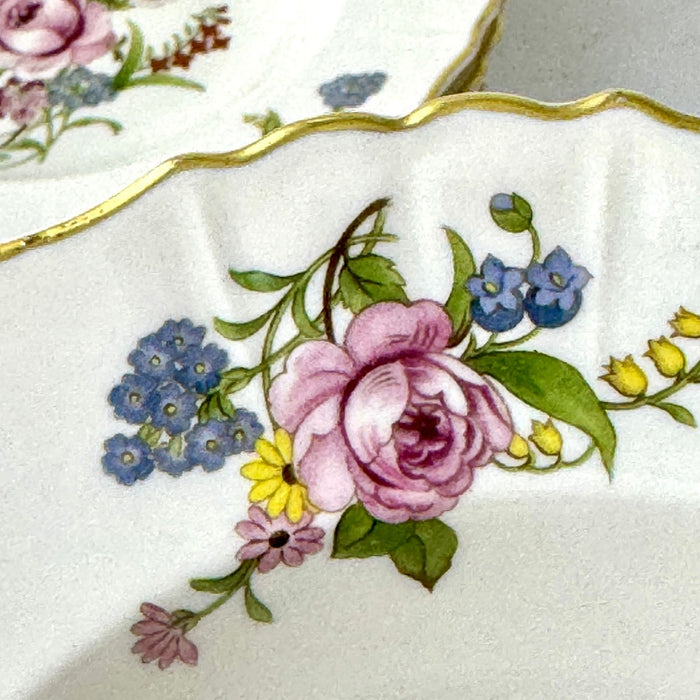Close-up of a floral spray on a Syracuse China Portland bowl with a pink rose, blue flowers, yellow flowers, and green leaves.