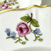 Close-up of a floral spray on a Syracuse China Portland bowl with a pink rose, blue flowers, green leaves, and gold-trimmed scalloped rim.
