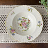 Vintage Syracuse China Portland floral soup bowl displayed on a crocheted table runner on a dark wood table.