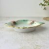 Side view of vintage porcelain trinket dish showing its shallow profile, scalloped gilded edge, and softly shaded interior.