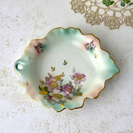Overhead view of Schumann Arzberg porcelain trinket dish showing its asymmetrical leaf form, mauve florals, aqua shading, and gold details.