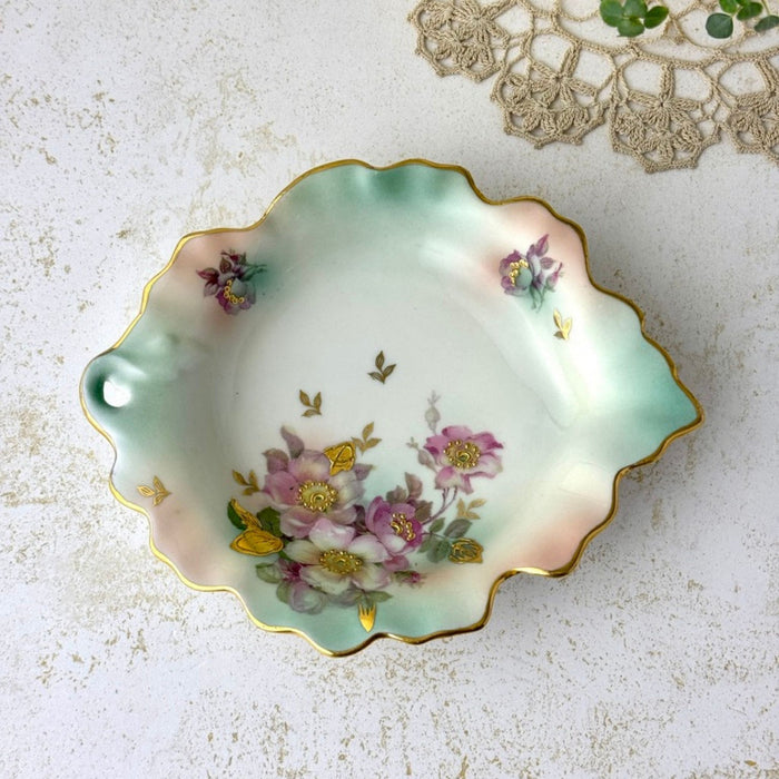 Overhead view of Schumann Arzberg porcelain trinket dish showing its asymmetrical leaf form, mauve florals, aqua shading, and gold details.