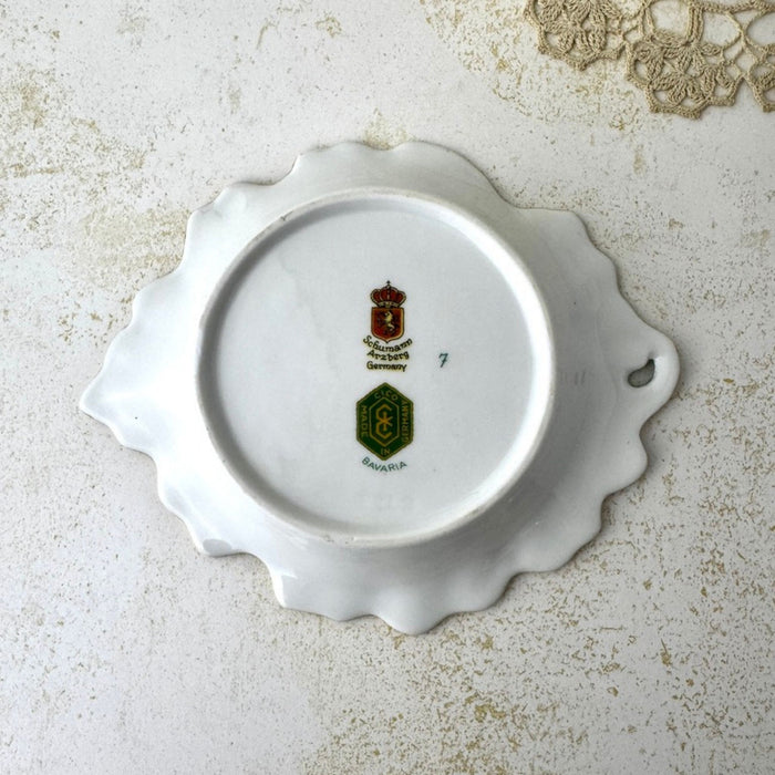 Underside of vintage Schumann Arzberg porcelain trinket dish showing the foot ring, leaf form, open loop, and maker marks.