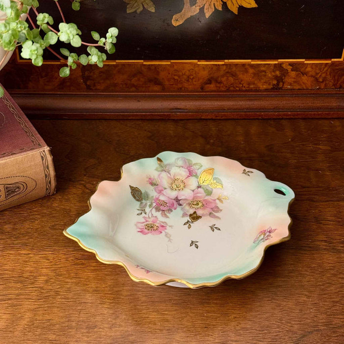Schumann Arzberg floral porcelain trinket dish styled on a dark wood surface with a vintage book and trailing plant.