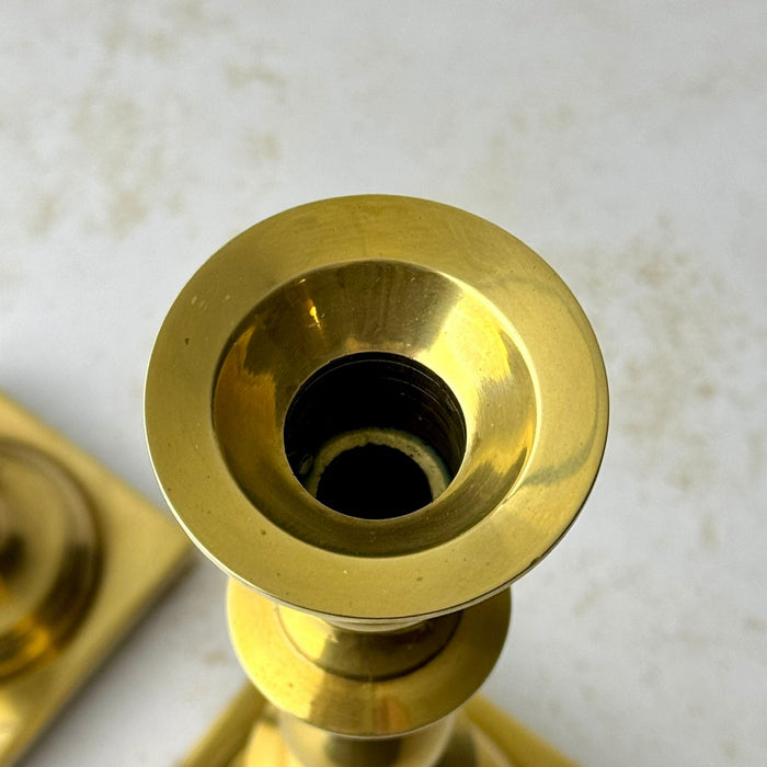 Overhead close-up of the taller brass candlestick showing its wide flared candle cup and standard taper opening.