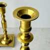 Close-up of the upper section of the taller brass candlestick showing its flared candle cup and turned brass details.