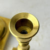 Overhead close-up of the shorter brass candlestick showing its flared candle cup and standard taper opening.