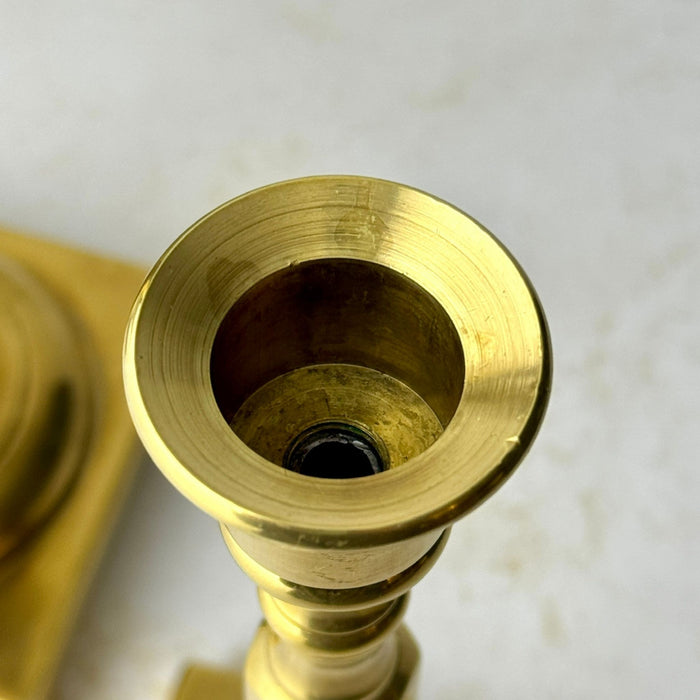 Overhead close-up of the shorter brass candlestick showing its flared candle cup and standard taper opening.