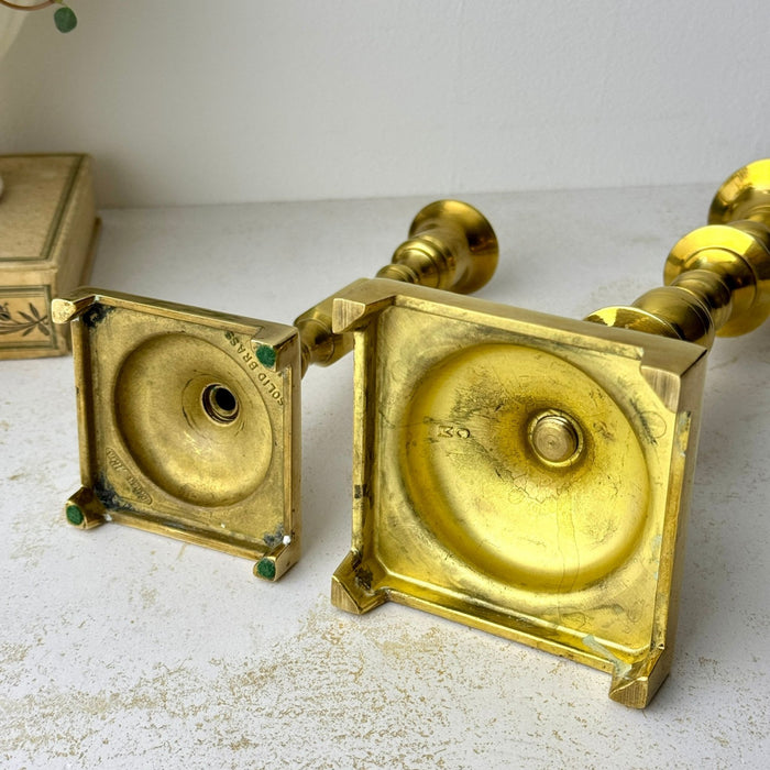 Underside view of both vintage brass candlesticks showing their square footed bases and maker markings.