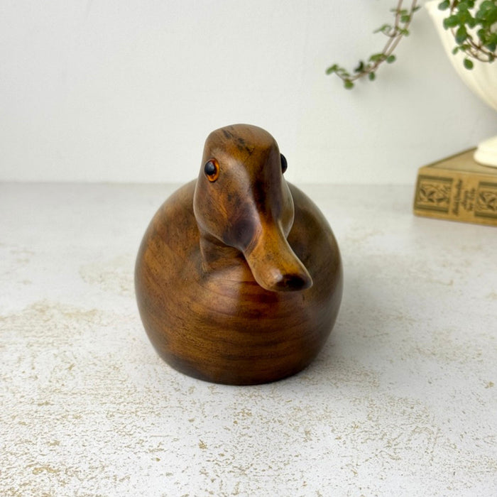 Front view of the carved wooden duck showing the narrow bill, rounded chest, and glass eyes.