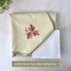 Folded warm cream tablecloth beside a white linen color reference, showing the tablecloth’s cream color and taupe scalloped edging.