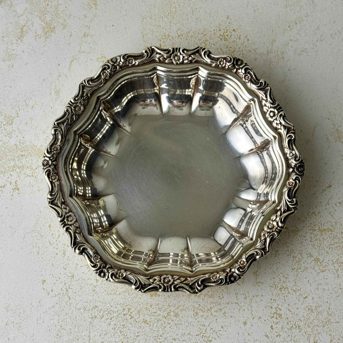 Overhead view of vintage International Silverplate bowl showing the fluted interior and ornate floral and scroll border.