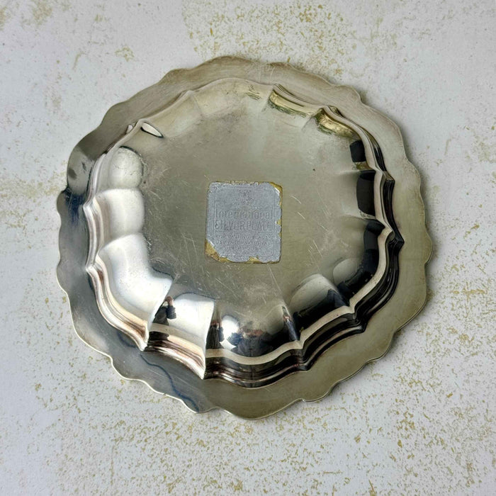 Underside of vintage silverplate bowl showing its fluted form and worn International Silverplate paper label.