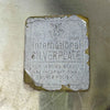 Close-up of worn International Silverplate paper label with crown and IS mark.