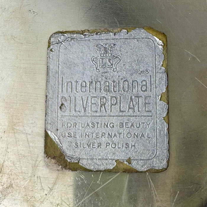 Close-up of worn International Silverplate paper label with crown and IS mark.
