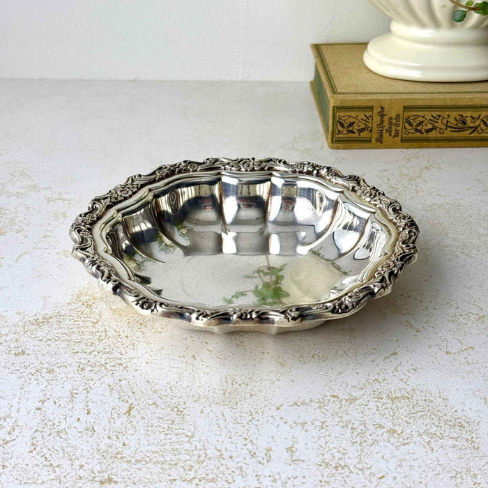 Vintage International Silverplate bowl with a fluted body and ornate raised floral and scroll border.