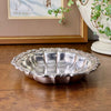Vintage International Silverplate bowl with ornate floral border displayed on a dark wood surface beside framed art and a green plant.
