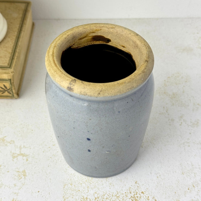 Angled overhead view of small gray-blue stoneware crock showing the thick buff rim and dark glazed interior.