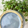 Close-up of underside of gray-blue stoneware crock showing the glazed center and broad unglazed buff foot ring.