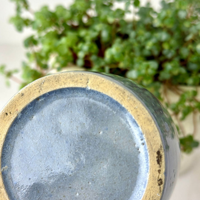 Close-up of underside of gray-blue stoneware crock showing the glazed center and broad unglazed buff foot ring.