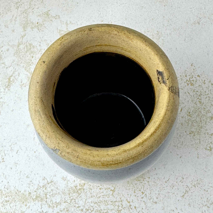 Overhead view of small stoneware crock showing the thick buff rim and very dark glazed interior.