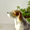 Close-up side profile of ceramic dog figurine showing the softly painted brown and gray markings and long ear.