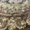 Close-up of the backside of the wool needlepoint showing the dense stitching and reverse construction in muted green, tan, cream, and brown.