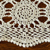 Close-up of an ecru crochet table runner showing a circular medallion, openwork crochet, and scalloped border against dark wood.