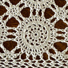 Close-up of a circular crochet medallion surrounded by openwork connections in an ecru table runner on dark wood.