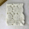 Overhead view of a neatly folded ecru crochet table runner showing repeating circular medallions, openwork, and scalloped edges.