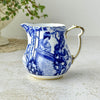 Royal Crown Derby Blue Mikado creamer with cobalt blue scenic decoration, white porcelain, and gold-trimmed scalloped rim.