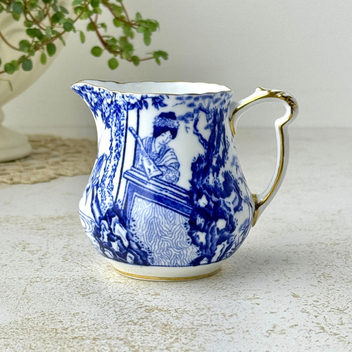 Royal Crown Derby Blue Mikado creamer with cobalt blue scenic decoration, white porcelain, and gold-trimmed scalloped rim.